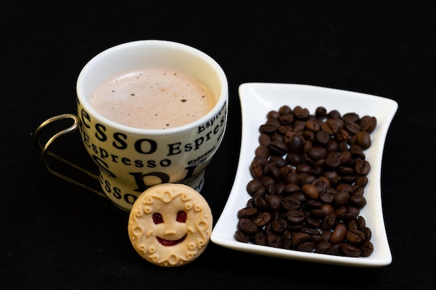 tazza di caffè chicchi di caffè e un biscotto sorridente