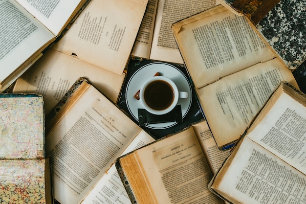 Tazza di caffè circondata da libri antichi aperti