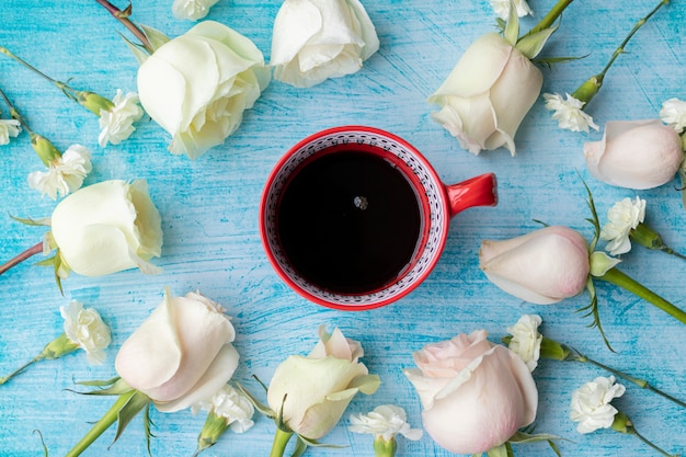 Tazza di caffè circondata da rose bianche