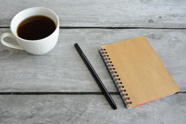 tazza di caffè con blocco note su sfondo grigio, primo piano