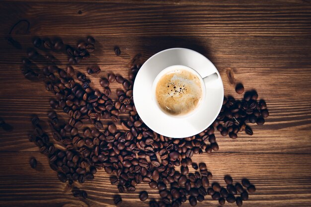 Tazza di caffè con chicchi di caffè sullo sfondo di legno