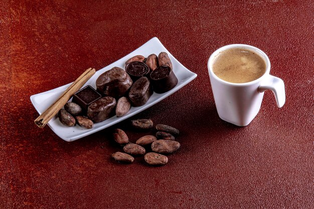 Tazza di caffè con cioccolatini fotografati su sfondo dipinto di marrone