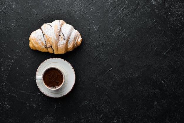 Tazza di caffè con croissant Colazione su sfondo di pietra nera Vista dall'alto Spazio libero per il testo