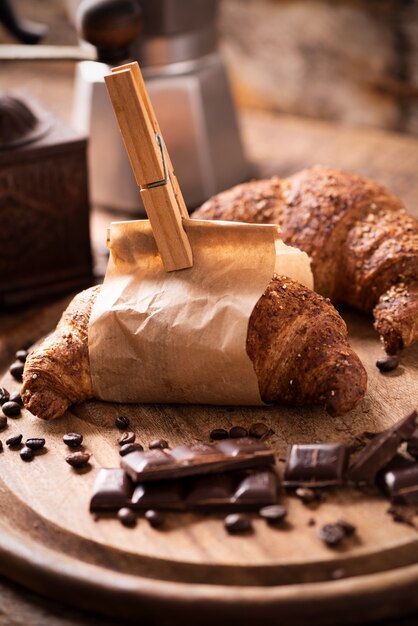 Tazza di caffè con croissant e caffè fresco su sfondo marrone