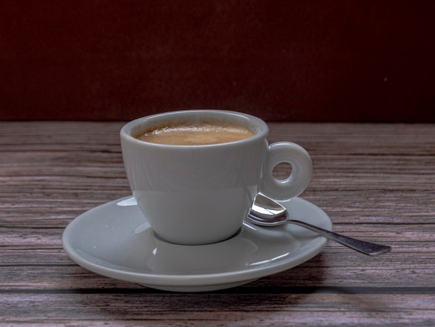 Tazza di caffè con cucchiaio su fondo rustico. Ha uno spazio negativo in alto.