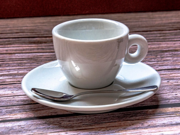 Tazza di caffè con cucchiaio su fondo rustico.