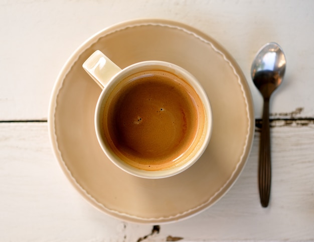 tazza di caffè con cucchiaio sul tavolo bianco