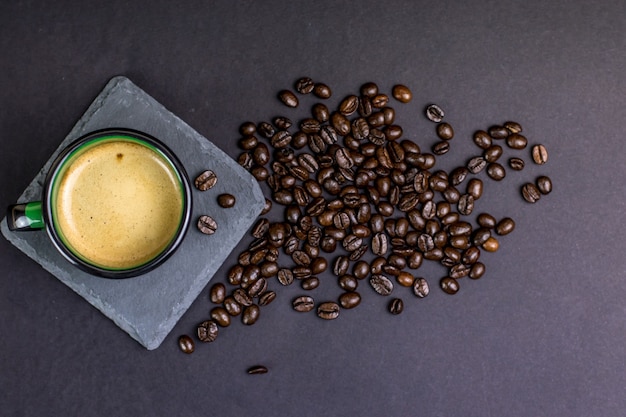 Tazza di caffè con fagioli in uno sfondo scuro