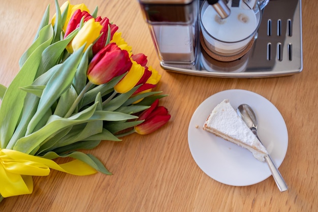 Tazza di caffè con fetta di torta al latte e tulipani