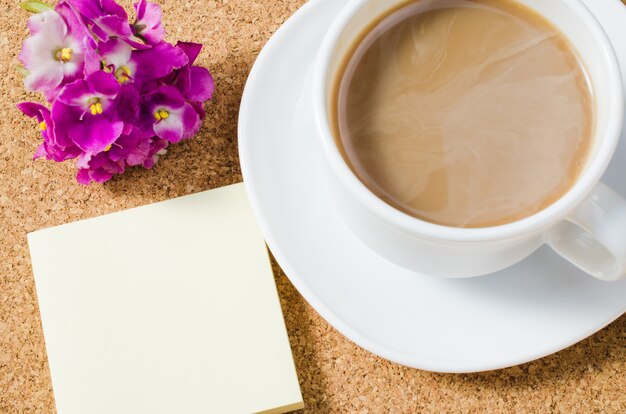 Tazza di caffè con fiori sul bordo di sughero.