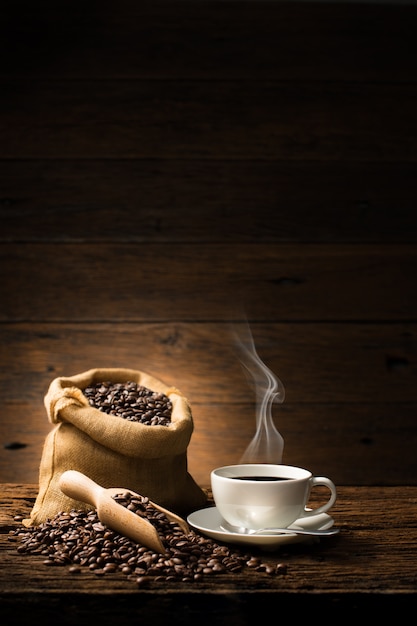 Tazza di caffè con fumo e chicchi di caffè su vecchio fondo di legno