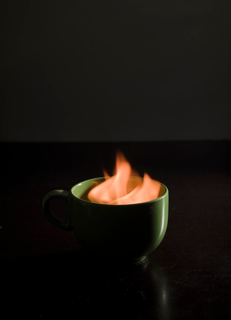 tazza di caffè con fuoco all'interno, sfondo nero