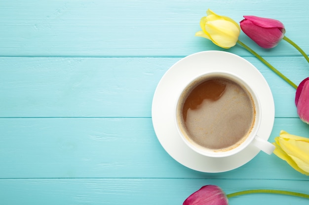 Tazza di caffè con i tulipani sulla superficie blu