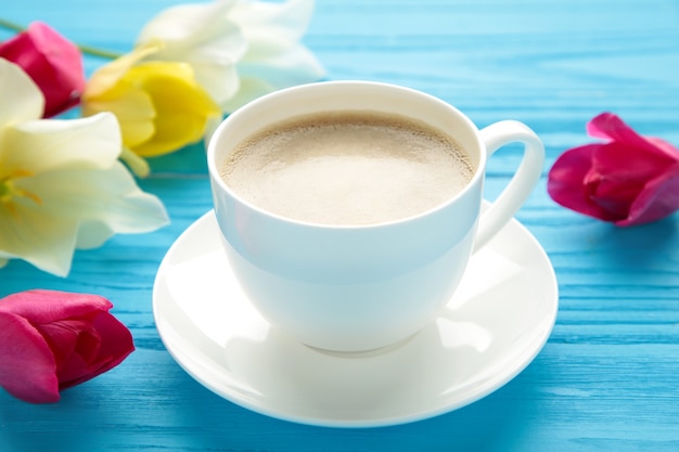 Tazza di caffè con i tulipani sulla superficie blu