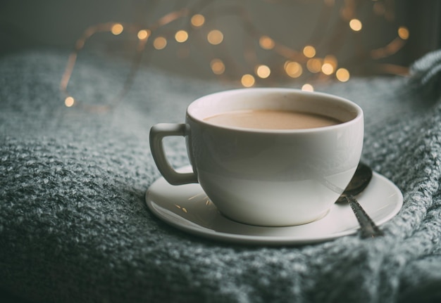 Tazza di caffè con latte su un'accogliente coperta invernale lavorata a maglia