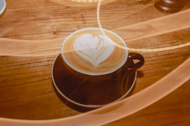 Tazza di caffè con latte su un tavolo con disegno a cuore e linee di dipinti leggeri