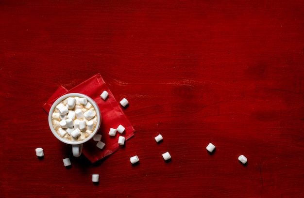 Tazza di caffè con marshmallow su fondo di legno rosso