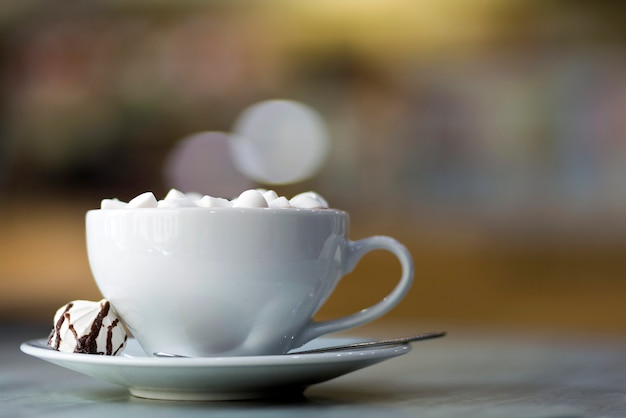 Tazza di caffè con marshmallow sul piatto di porcellana