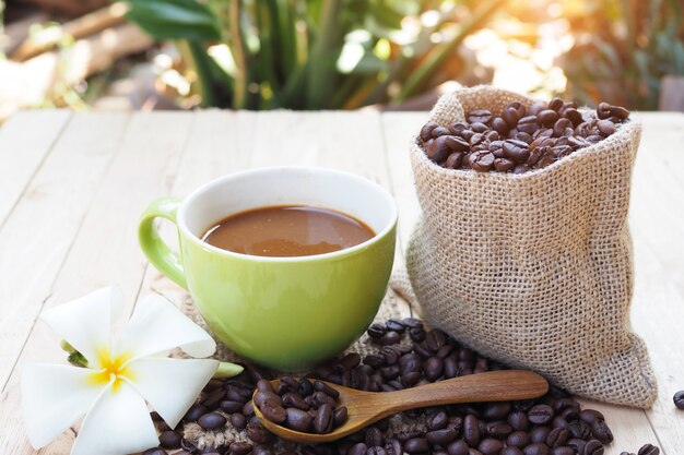 Tazza di caffè con sacco di iuta di chicchi di caffè sul tavolo di legno