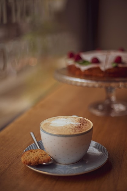 Tazza di caffè con un motivo a cuore in una tazza su un piattino su uno sfondo di legno in un caffè