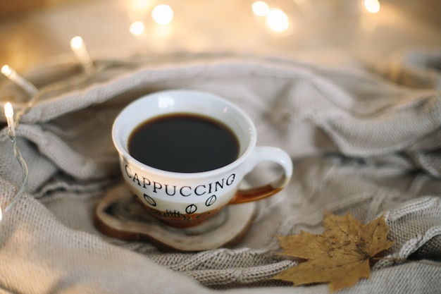 tazza di caffè con un plaid beige lavorato a maglia su sfondo autunno e inverno accogliente concetto di svago