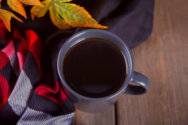 Tazza di caffè, coperta e foglie di autunno.