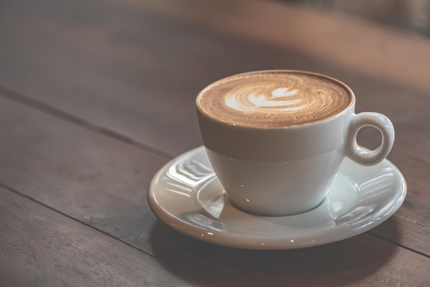 Tazza di caffè d'arte latte o cappuccino sulla tavola di legno