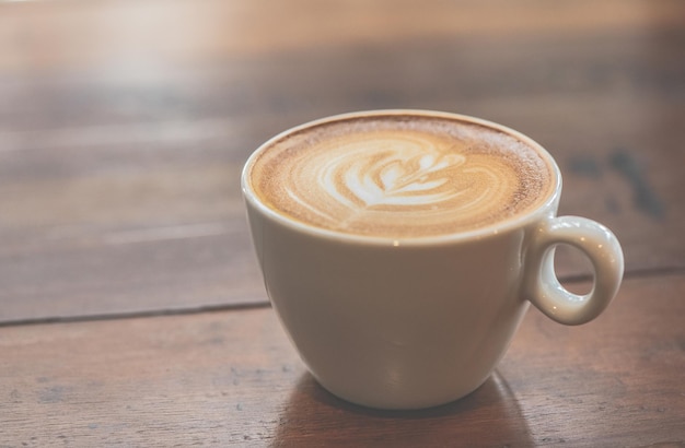 Tazza di caffè d'arte latte o cappuccino sulla tavola di legno