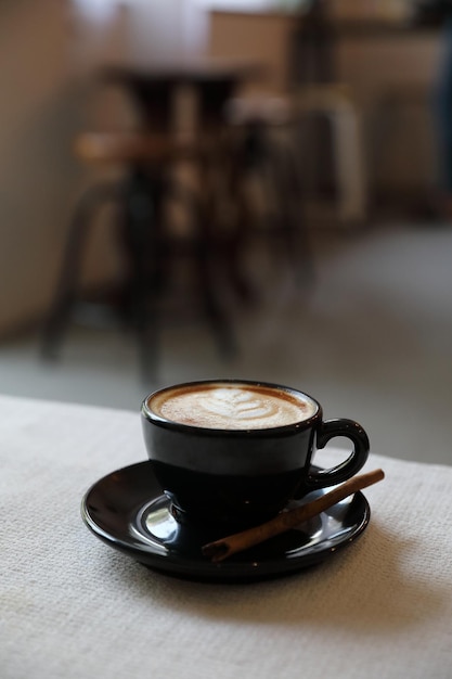 Tazza di caffè del cappuccino su fondo bianco del tessuto