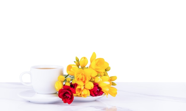 Tazza di caffè del mattino e fiori su sfondo bianco