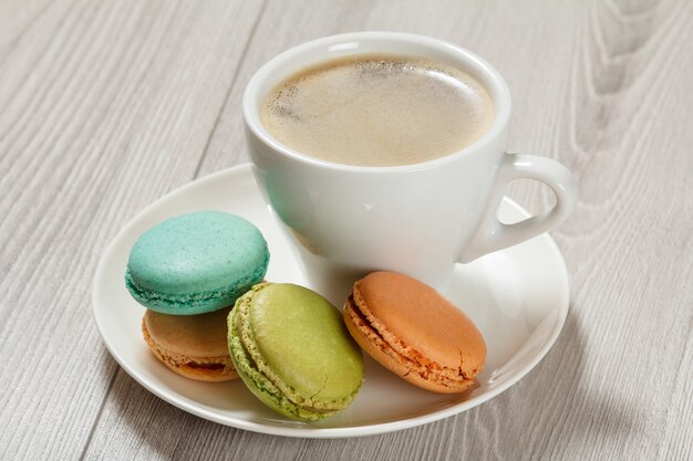 tazza di caffè deliziose torte di macarons di colore diverso su un piatto di porcellana bianca