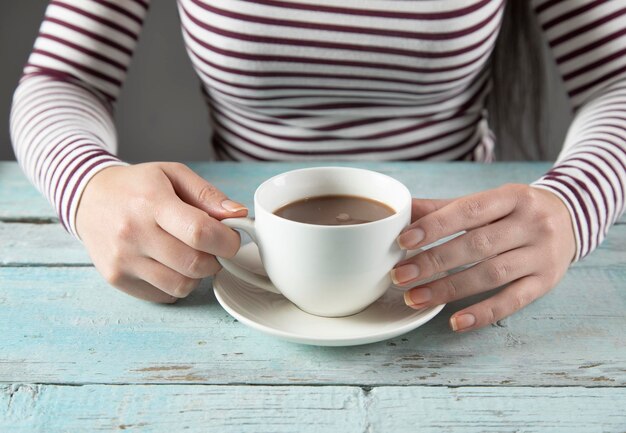 Tazza di caffè della mano della donna