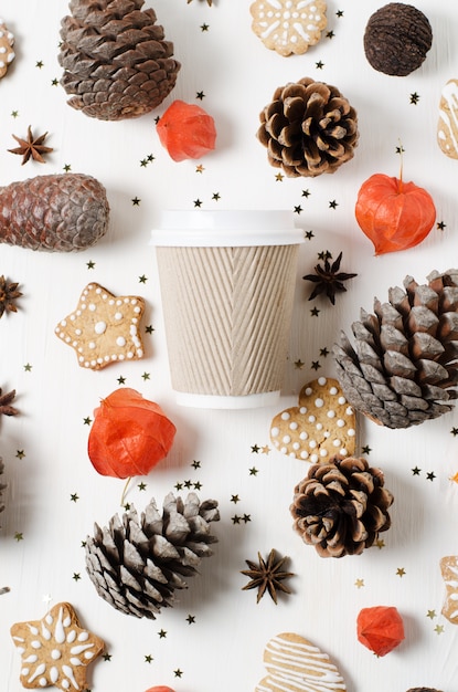 Tazza di caffè di carta da asporto tra biscotti, pigne e altre decorazioni natalizie. Vista dall'alto