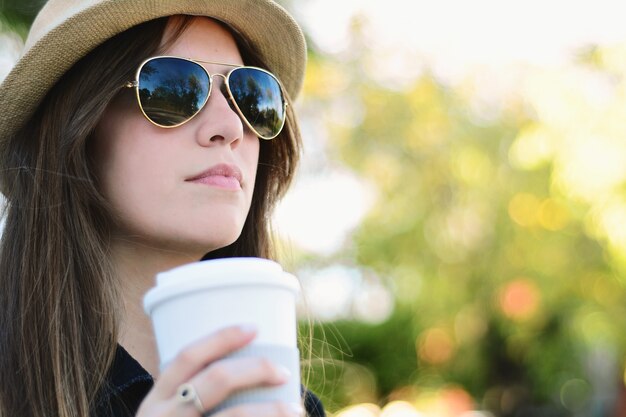 Tazza di caffè di carta della tenuta della donna nella via.