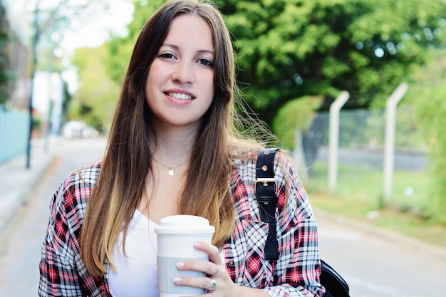 Tazza di caffè di carta della tenuta della donna nella via.