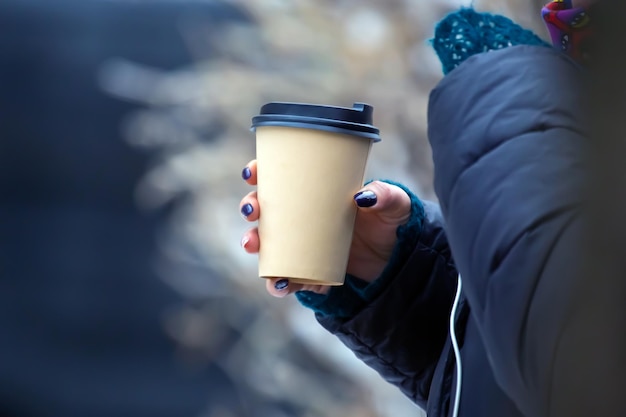 Tazza di caffè di carta in una mano di donna per strada