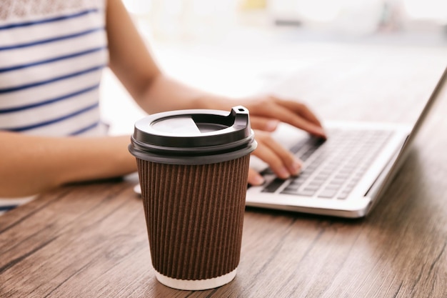 Tazza di caffè di carta sul primo piano di legno della tavola