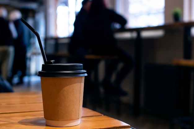 Tazza di caffè di carta sul tavolo nella caffetteria