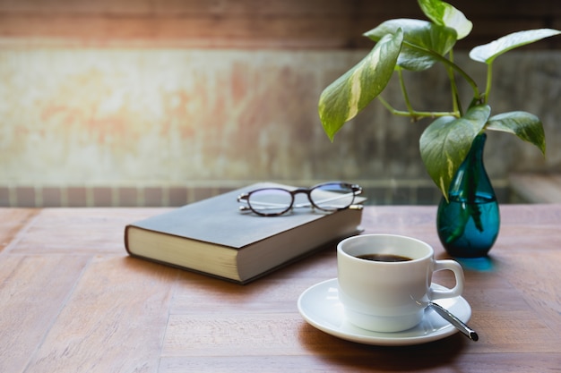 Tazza di caffè e bicchieri in cima a readbook sul tavolo di legno.