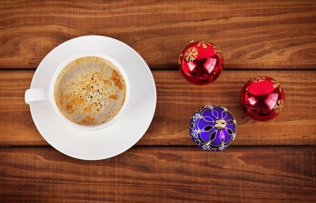 Tazza di caffè e bolle di Natale su fondo di legno.