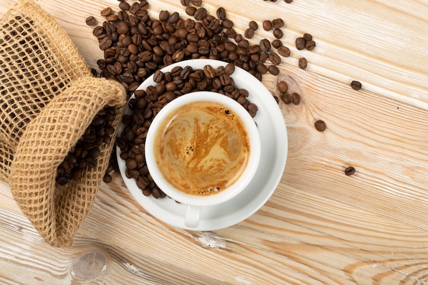 Tazza di caffè e chicchi di caffè caldi sulla vista superiore del fondo marrone
