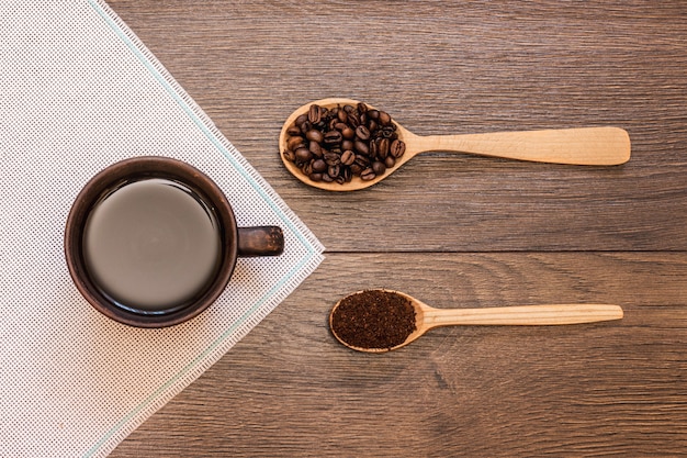 Tazza di caffè e chicchi di caffè in cucchiai di legno