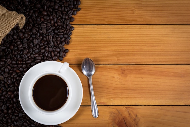 Tazza di caffè e chicchi di caffè in un sacco su legno