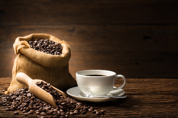 Tazza di caffè e chicchi di caffè su vecchio fondo di legno