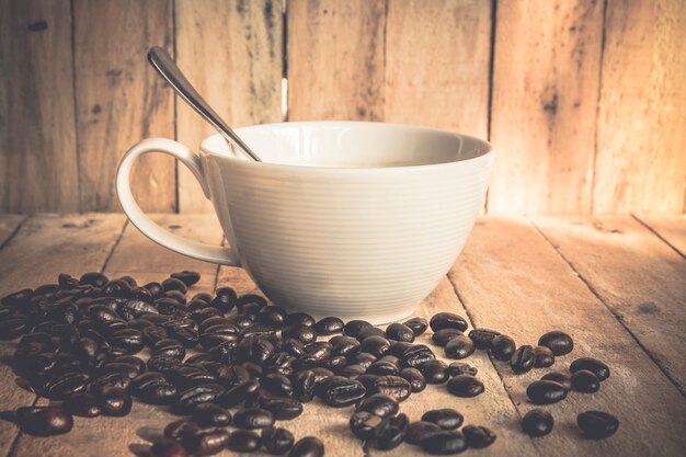 Tazza di caffè e chicchi di caffè su vecchio fondo di legno