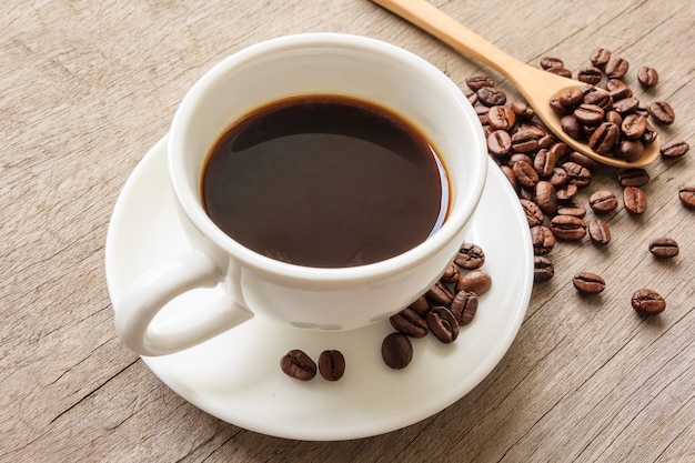 Tazza di caffè e chicchi di caffè sul tavolo di legno