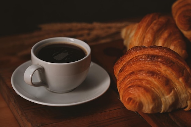 Tazza di caffè e croissant appena sfornati tavolo in legno Pane a levitazione prodotti da forno concetto di caffè