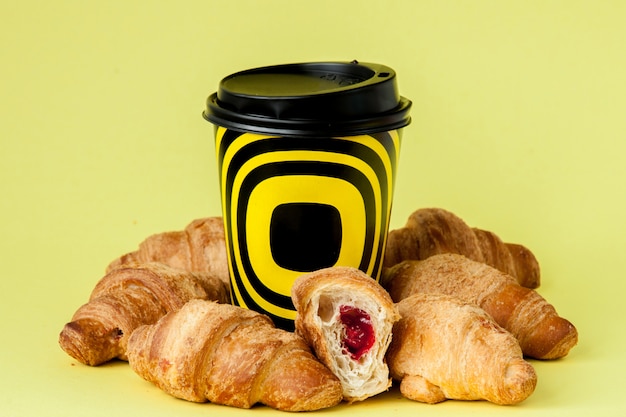 Tazza di caffè e croissant di carta su giallo