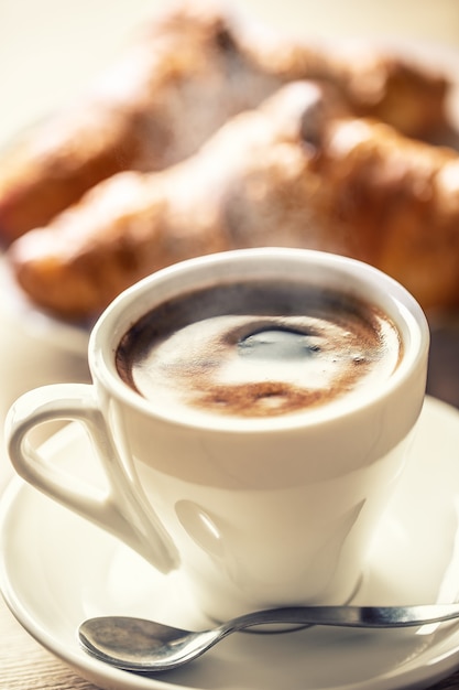 Tazza di caffè e croissant freschi - colazione italiana o mediterranea.