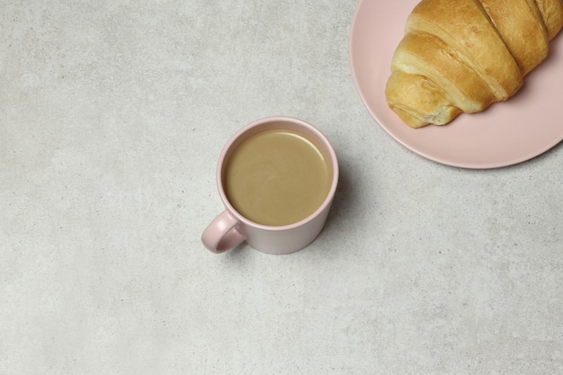 Tazza di caffè e croissant rosa sul fondo del granito